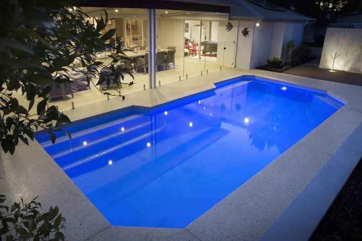 Home Pool with Concrete Surrounds at night time with blue water light